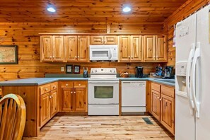 A kitchen with wooden cabinets, a microwave, a stove, and a dishwasher. - Spacious cabin, Pigeon Forge-GSMNP-Relaxing & fun (Sevierville)