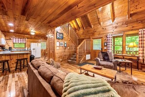 Ein Holzblockbau-Innenraum mit Küche, Wohnbereich und einer Treppe.