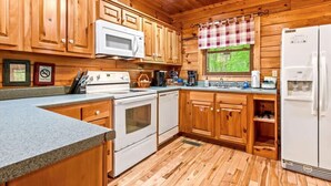 A kitchen with wooden cabinets, a microwave, a stove, and a refrigerator. - Spacious cabin, Pigeon Forge-GSMNP-Relaxing & fun (Sevierville)