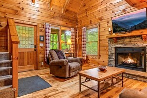 A wooden cabin interior with a fireplace, a sofa, a television, and a dining area. - Spacious cabin, Pigeon Forge-GSMNP-Relaxing & fun (Sevierville)