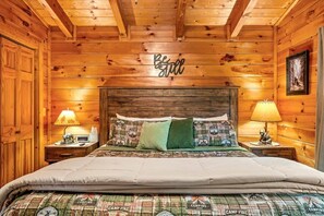 Ein schlicht eingerichtetes Schlafzimmer im Chalet-Stil mit einem Bett, zwei Nachttischlampen und einem Schild mit der Aufschrift 'Be still'.