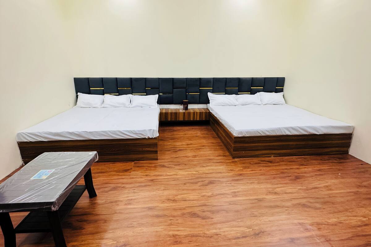 Une chambre avec deux lits, un plancher en bois et une petite table.