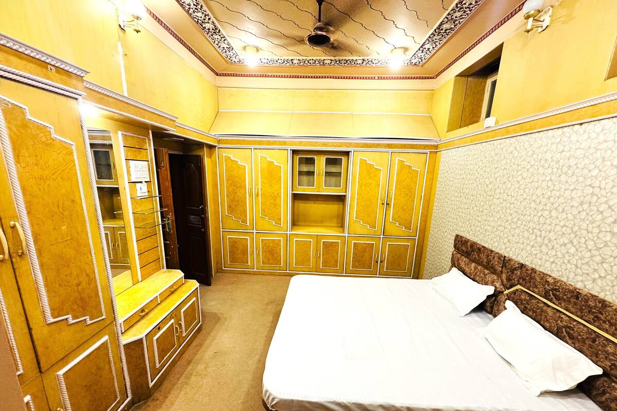Une chambre avec un grand lit, une armoire et une petite fenêtre.