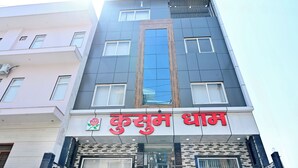 A multi-story building with a prominent sign reading "Kusum Dhama". - Kusum Dham By Reverie (Vrindavan)