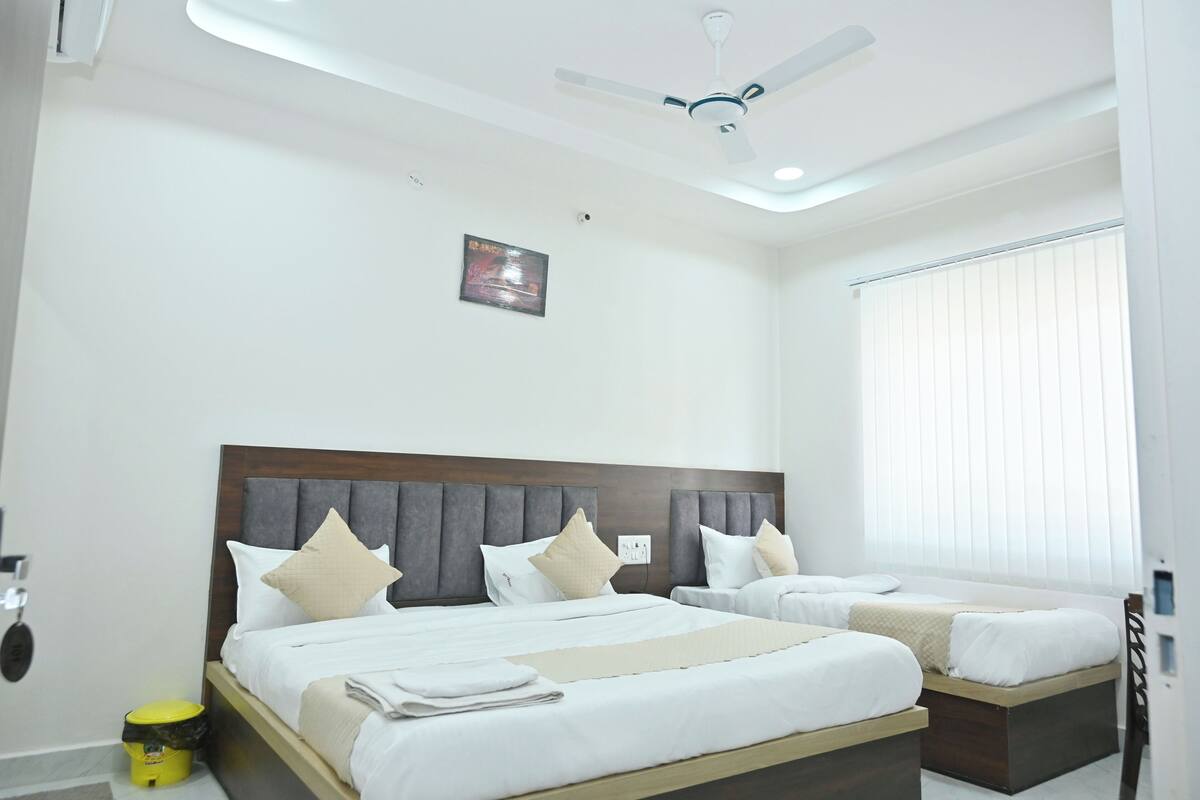 A hotel room with two beds, a ceiling fan, a window with blinds, and a small picture on the wall.