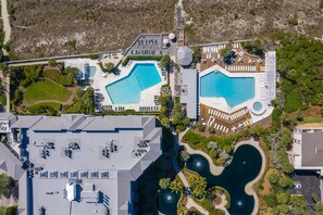Vue aérienne d’un complexe hôtelier doté de deux grandes piscines, d’un terrain de golf et d’un parking.