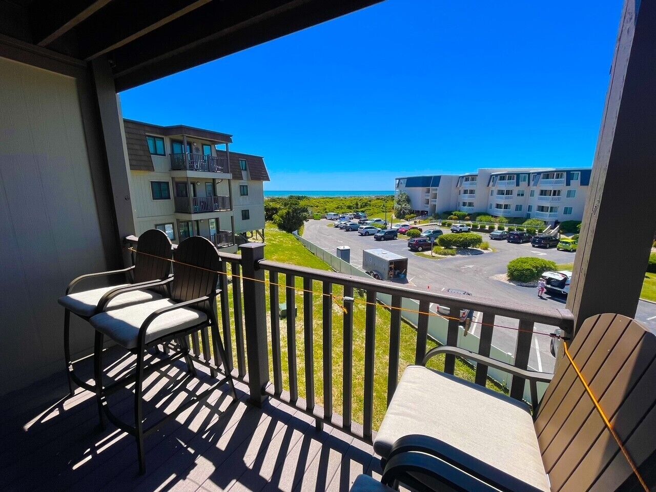 A balcony with chairs and a view of a parking lot and buildings.