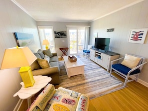 A living room with a sofa, a coffee table, a TV, and a chair.