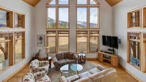 Un salón amplio con ventanas grandes, televisor y un rincón de estar acogedor.