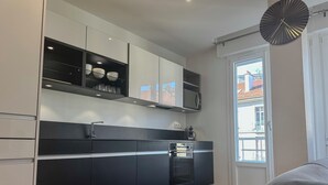 A modern kitchen with black and white cabinetry, a built-in oven, and a window with a view of buildings outside. - #HU | Le Coeur Lorraine 🥐  | City center/Station T3 (Grenoble)