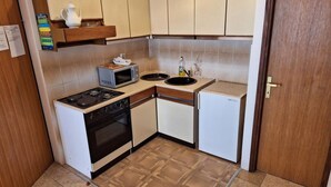 A compact kitchen with a stove, microwave, sink, and a small refrigerator. - apartman Štefica 2 with AC and WIFI (Punat)