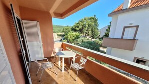 A balcony with a table and chairs, a sliding door, and a view of a residential area. - apartman Štefica 2 with AC and WIFI (Punat)
