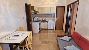 A compact living space with a dining table, chairs, a sofa, and a kitchenette. - apartman Štefica 2 with AC and WIFI (Punat)