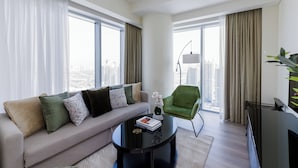 Een moderne woonkamer met een bank, groene fauteuil en een salontafel.