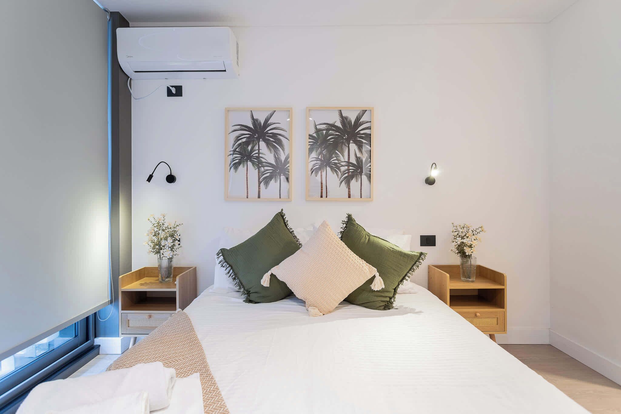 A modern bedroom with a large bed, two nightstands, a window, and wall-mounted artwork.