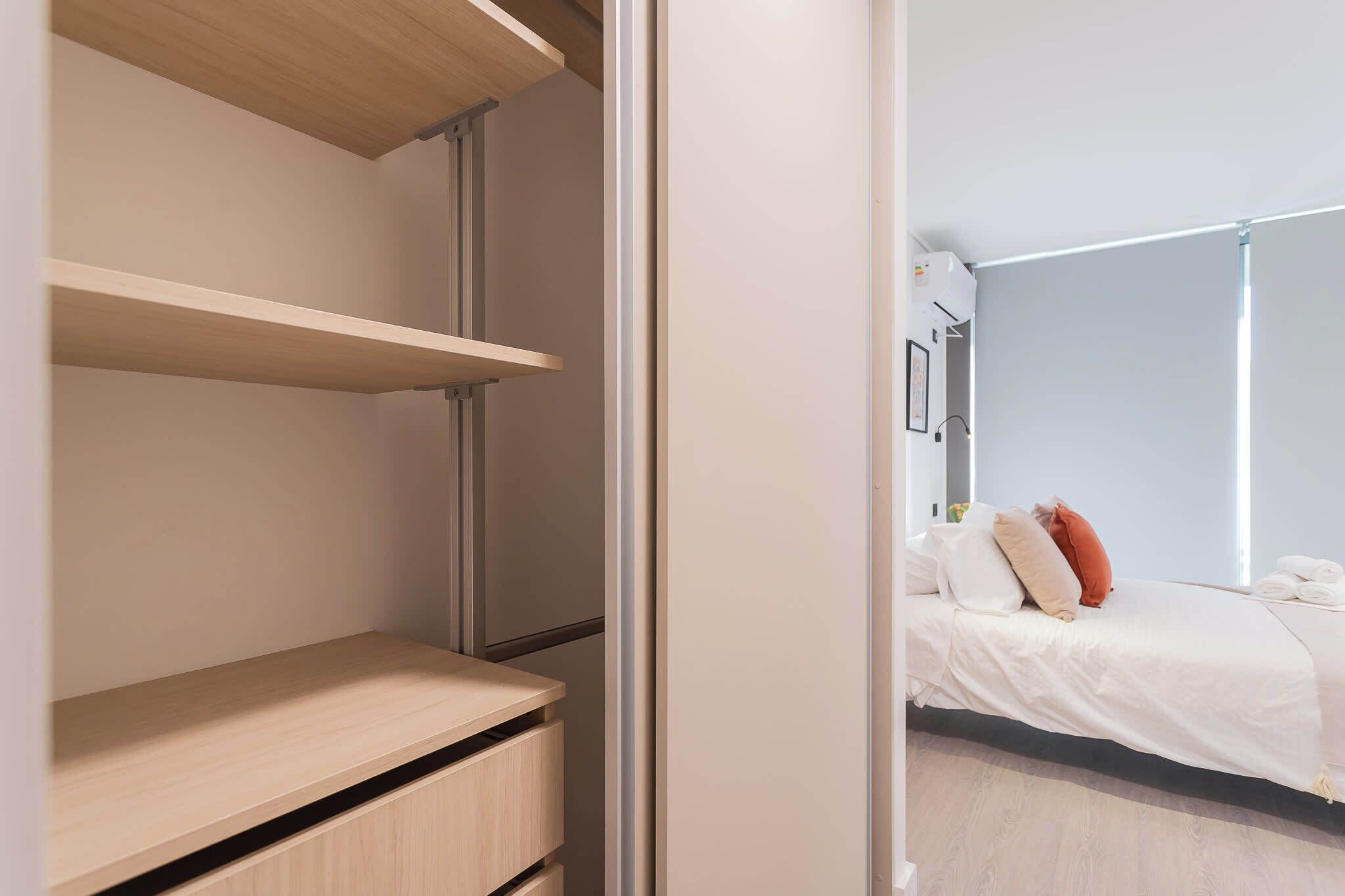 Une chambre à coucher moderne avec un lit, une table de chevet et une armoire intégrée dotée d’étagères.
