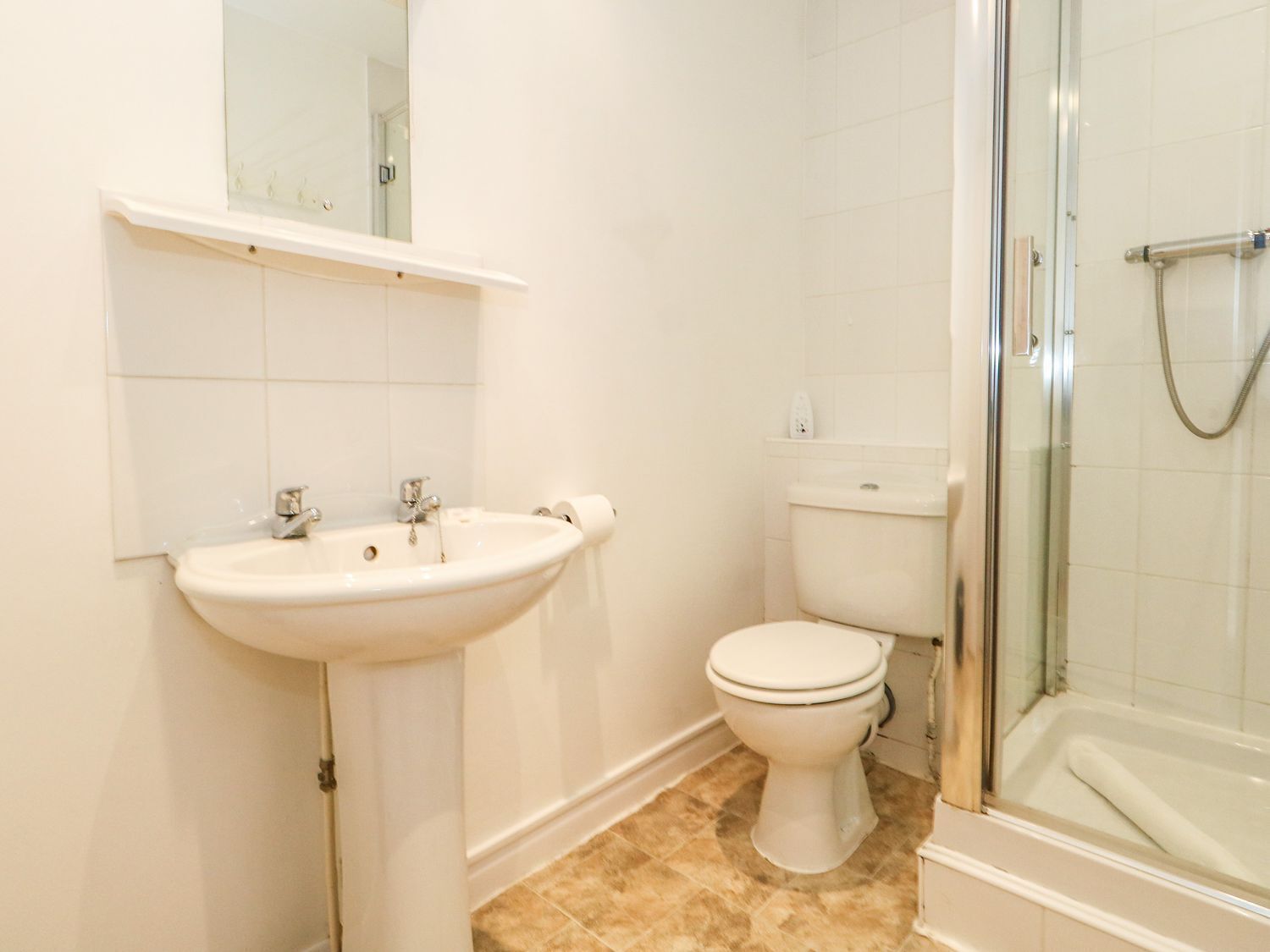 A bathroom with a white sink, toilet, and glass-enclosed shower.