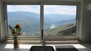 A kitchen with a large window, a sink, and a vase with flowers. - Luxury Douro Villa | Private pool, river views & BBQ Terrace (Vila Marim, Mesão Frio)