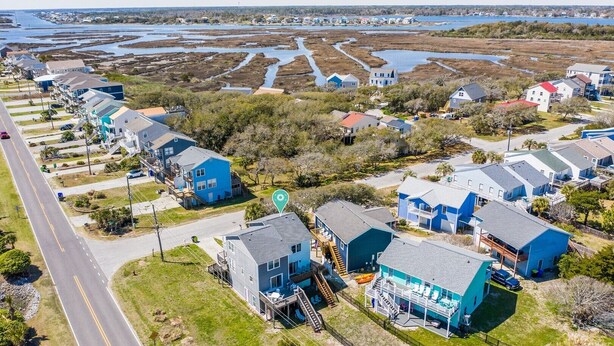 Une zone résidentielle côtière avec des maisons, une route et une étendue d’eau en arrière-plan.