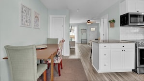Une cuisine moderne avec des meubles blancs, un four à micro-ondes encastré et une cuisinière en acier inoxydable.