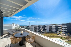 A balcony with a round table and chairs, overlooking a residential area with modern buildings and a clear sky. - The Panorama Penthouse – Penthouse with Pool and Sea Views | Fuengirola (Fuengirola)