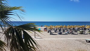 A beach with rows of sun loungers and thatched umbrellas, a clear blue sky, and the ocean in the background. - La Vida Feliz Andalucia – Andalusian Garden, Sea Views | Higueron West, Fuengirola (Fuengirola)
