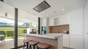 A modern kitchen with a central island, bar stools, and a view of a landscaped garden. - Garden Villa - Large Terrace with Outdoor Kitchen and Pool, Higueron West, Fuengirola (Fuengirola)