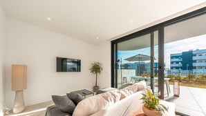 En moderne stue med sofa, TV og en plante.