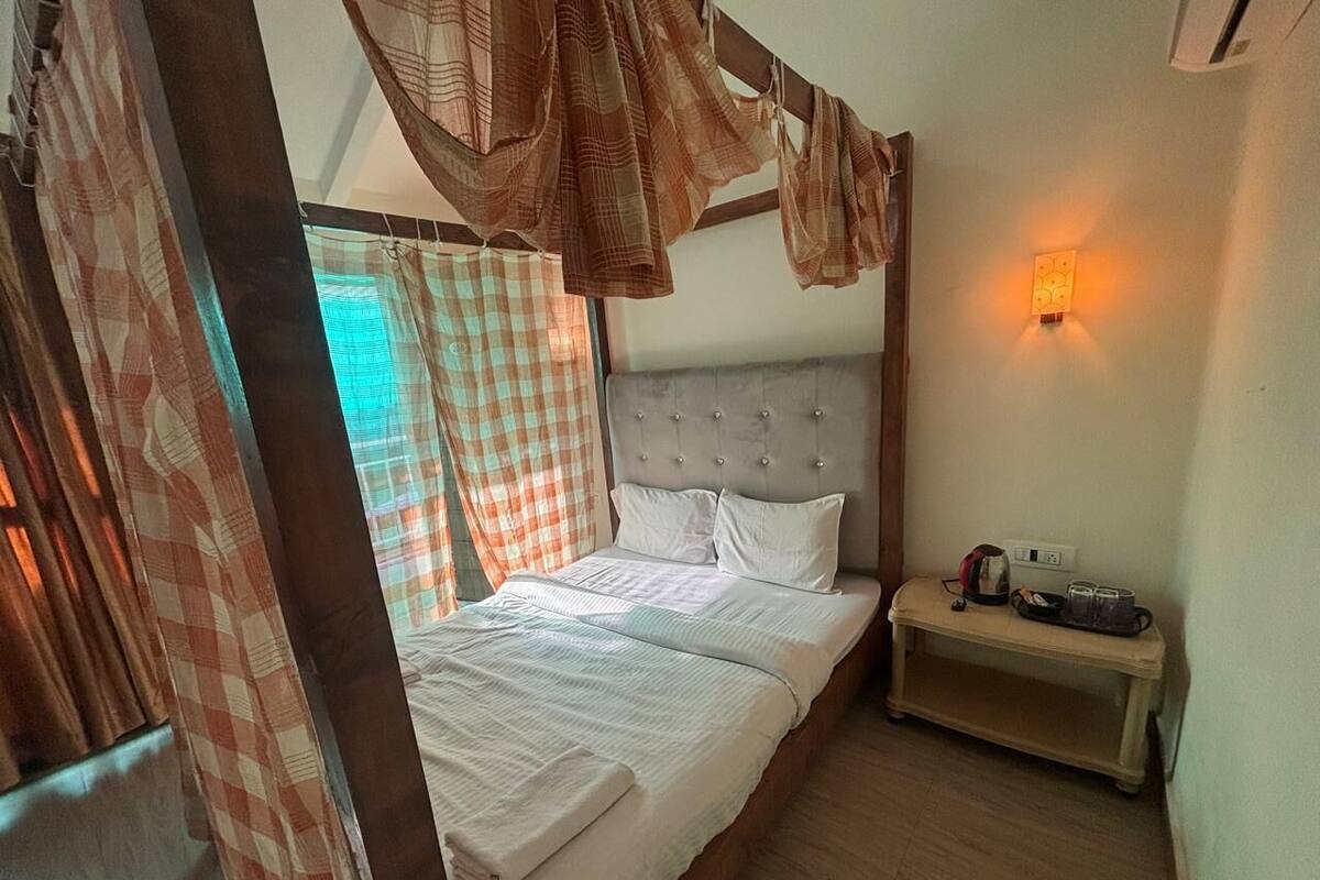 A bedroom with a bed, a bedside table, and a wall-mounted light.