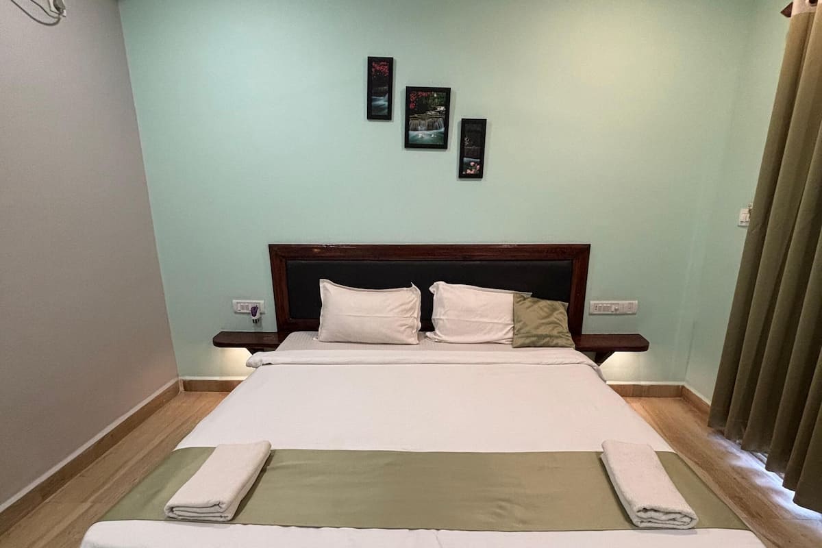 A neatly made bed with a wooden headboard, a bedside table, and a wall-mounted light fixture.