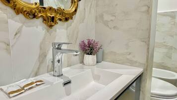 A bathroom with a white sink, a gold-framed mirror, and a marble wall.