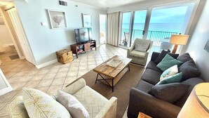 A living room with a sofa, armchair, coffee table, TV, and a view of the sea. - Beach front Gulf Views Golf Cart 4112 BS1 (Miramar Beach)