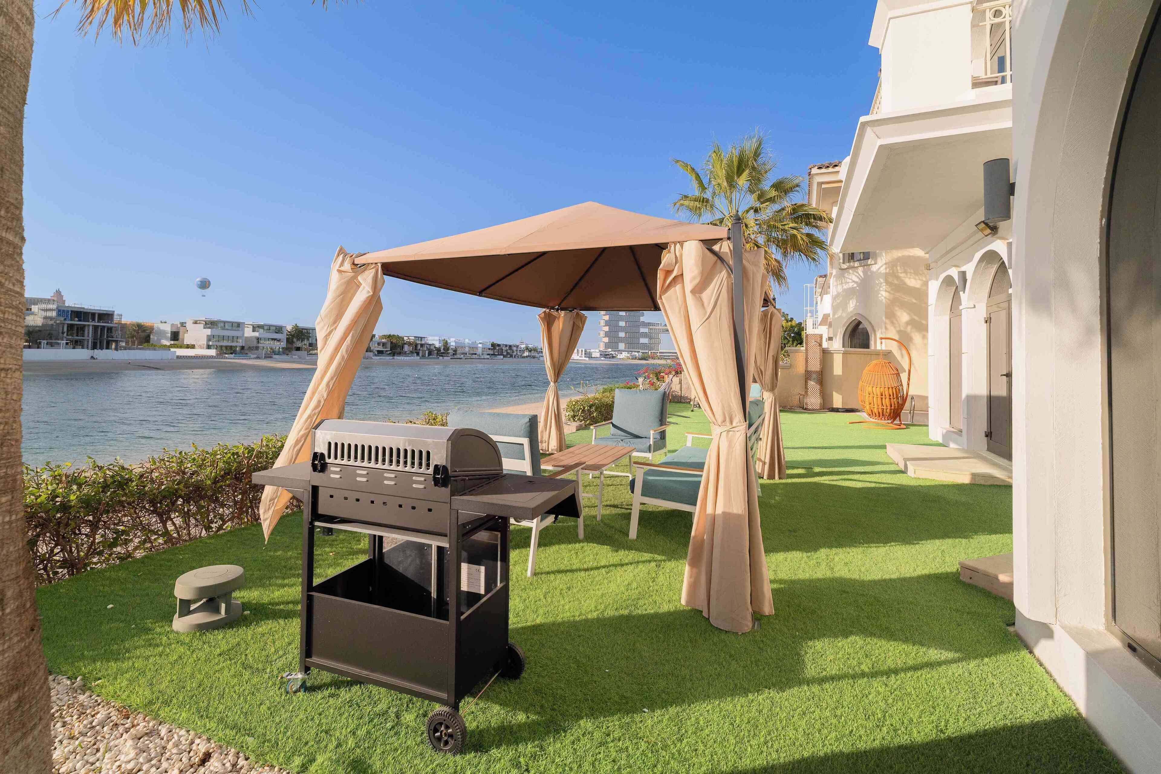 Une terrasse avec un barbecue, des sièges d’extérieur et une vue sur l’eau.