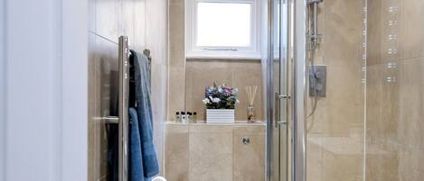 Une salle de bain moderne avec une douche à l’italienne en verre, des toilettes et un tapis bleu.