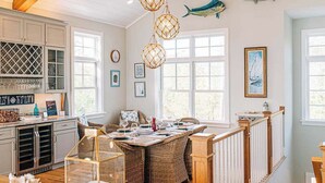 A dining area with wicker furniture, a bar with wine glasses, and decorative fish on the wall.