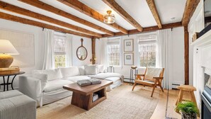 Una sala de estar acogedora con un sofá blanco, una mesa de centro de madera y una chimenea.