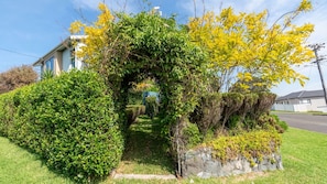 A garden with a stone wall, a pathway, and a house in the background.