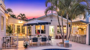 A poolside area with a dining setup, outdoor bar, and a pool. - Grand Residence | Heated Pool | Beach Proximity | Emerald Key | RESlDENCES (West Palm Beach)