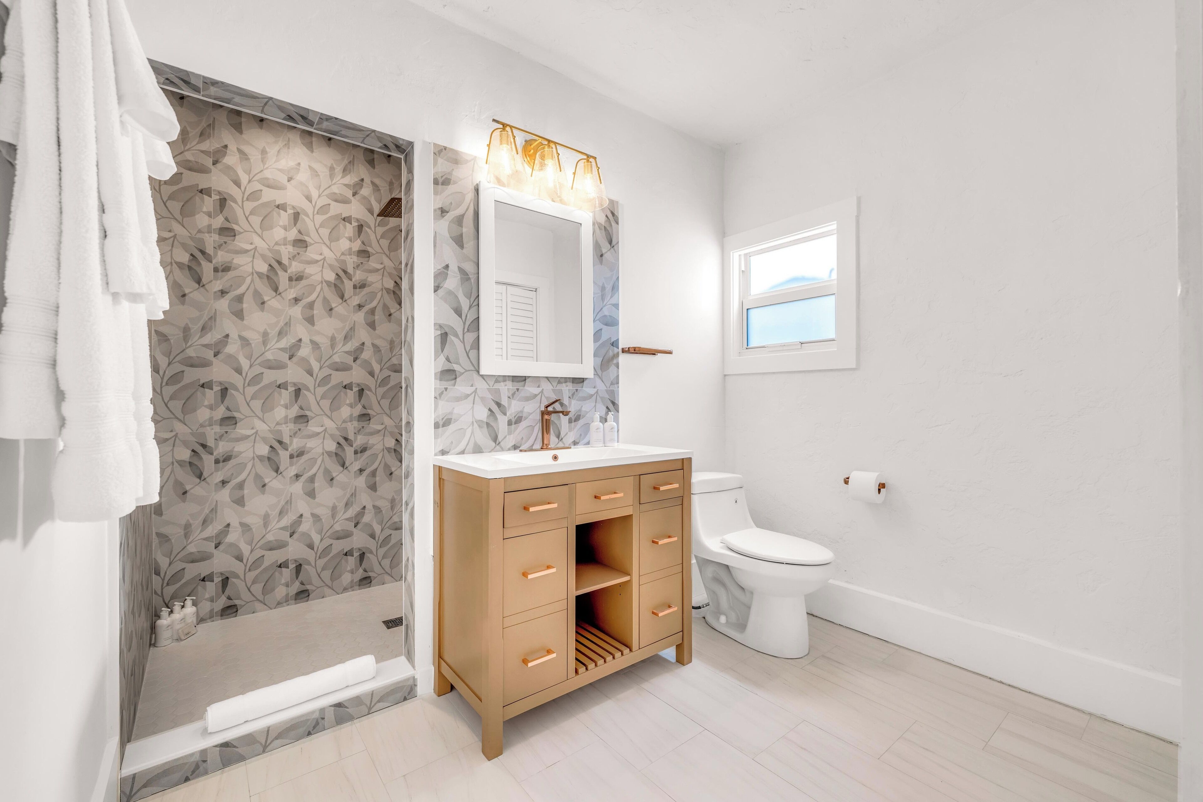 Ein modernes Badezimmer mit einem Holz-Waschtisch, einer Glasdusche und einer Toilette.