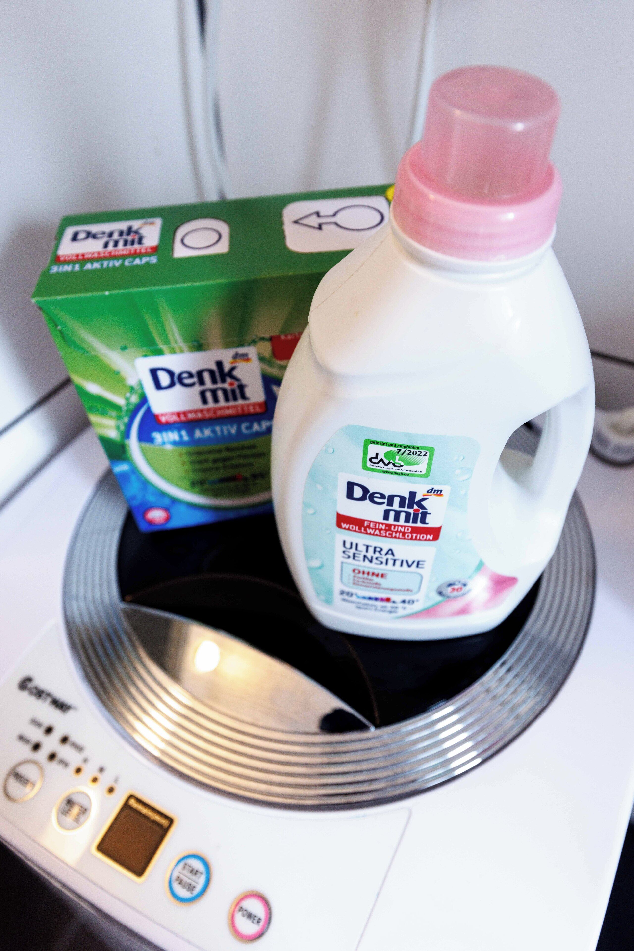 A washing machine with a bottle of Denki mit detergent and a box of the same brand.