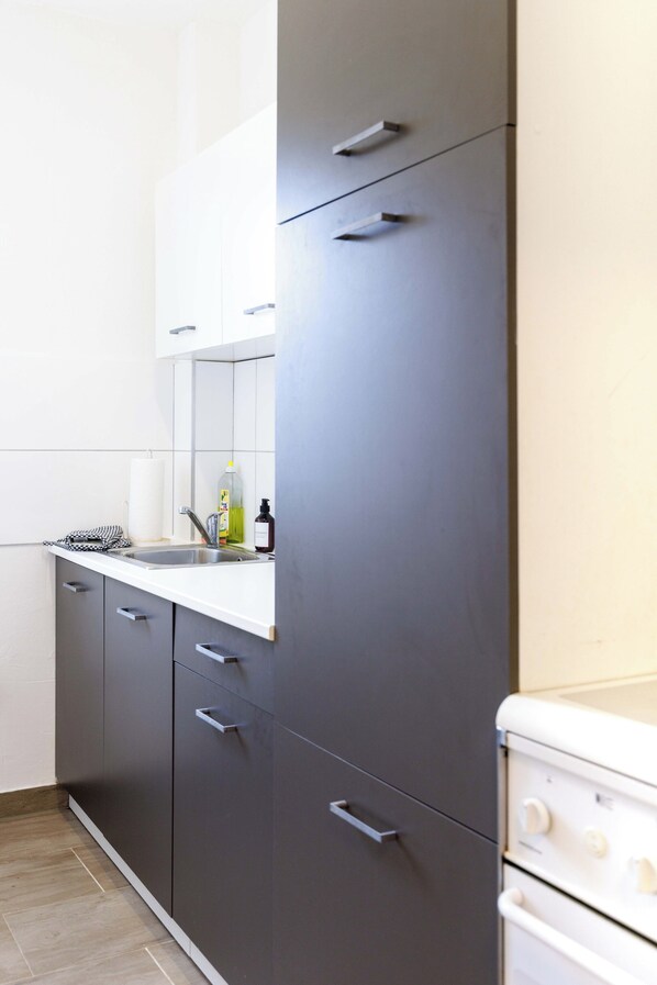 A modern kitchen with grey cabinets, a white countertop, and a white stove.