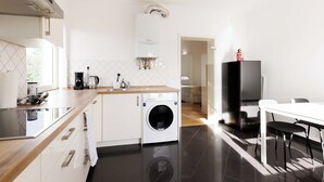 A modern kitchen with a built-in washer, a coffee maker, and a refrigerator. - Apartmenthaus - Kaiserslautern (Kaiserslautern)