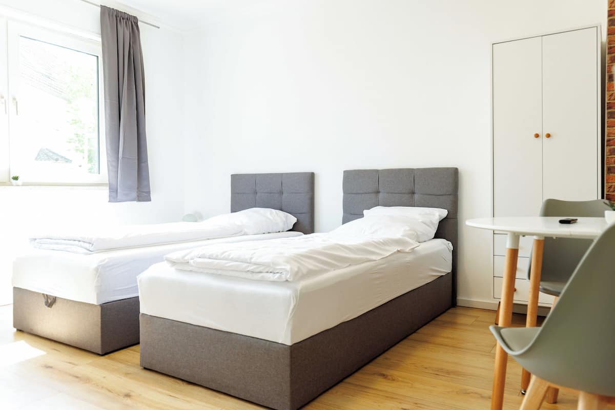 Un dormitorio moderno con dos camas, una mesita y un armario.