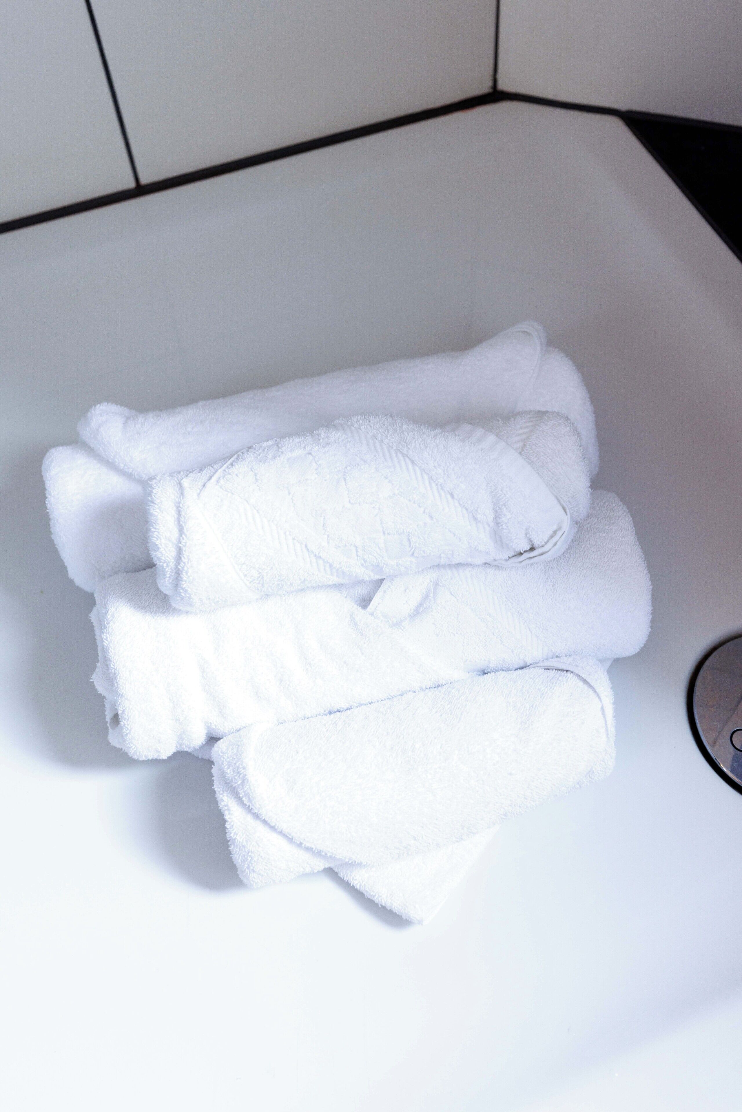 Une pile de serviettes blanches dans le lavabo d’une salle de bain.