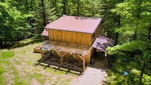 Une cabane en bois avec un toit en pente, une terrasse en bois et un chemin de gravier.
