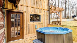 Une cabane en bois avec un jacuzzi, une porte et une fenêtre.