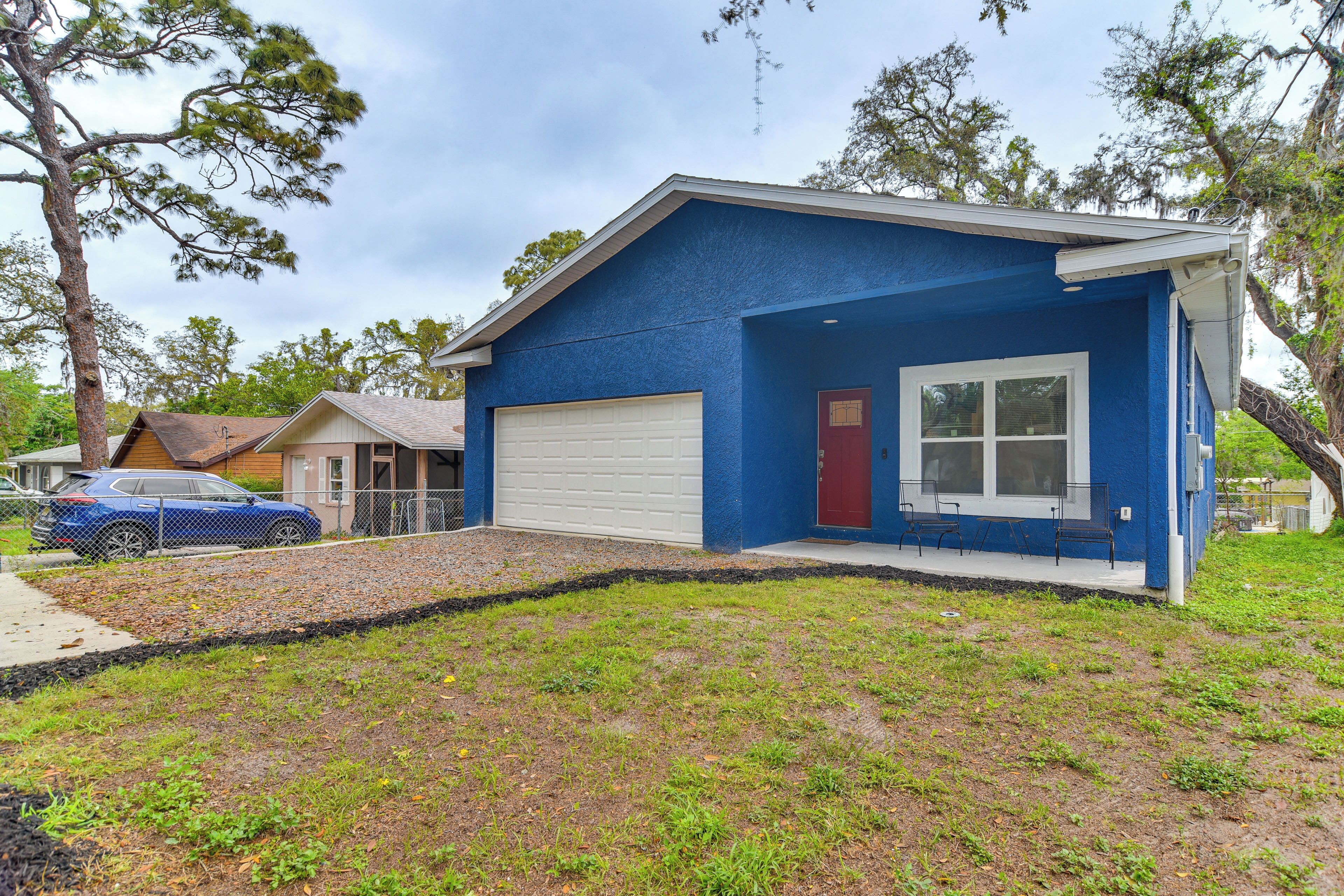 A single-story house with a blue exterior, a white garage door, and a red door.