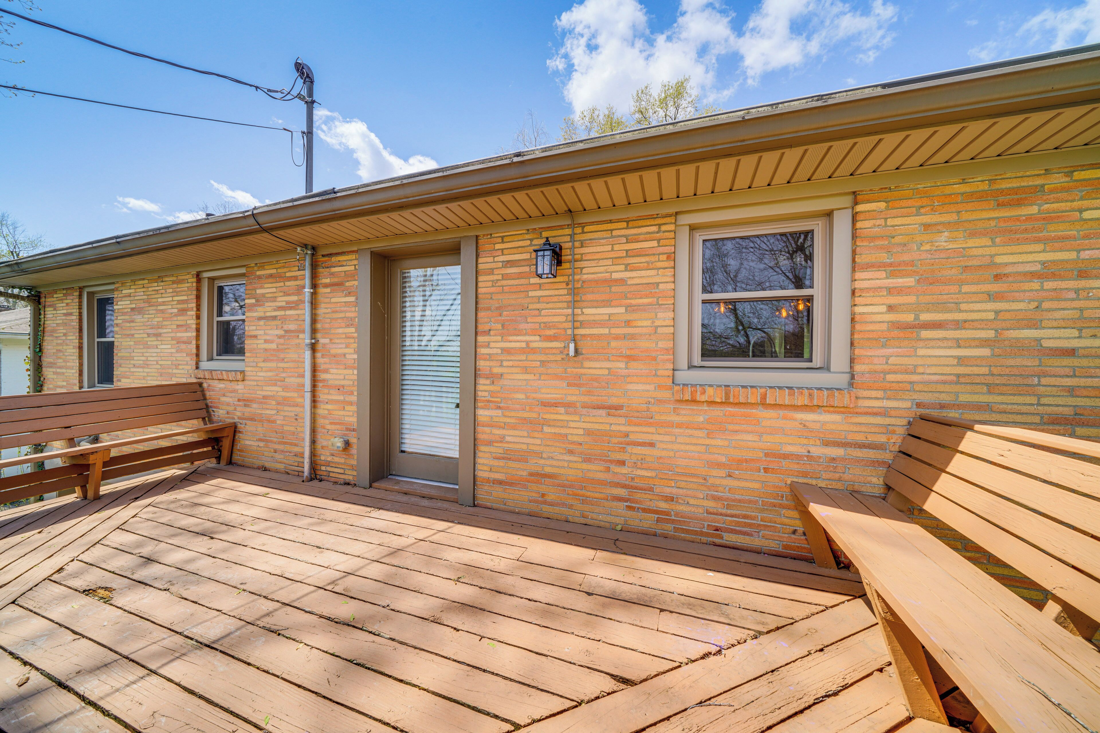A single-story brick building with a wooden deck and two benches.