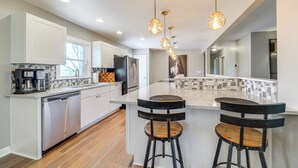 A modern kitchen with white cabinets, stainless steel appliances, and a central island with bar stools.