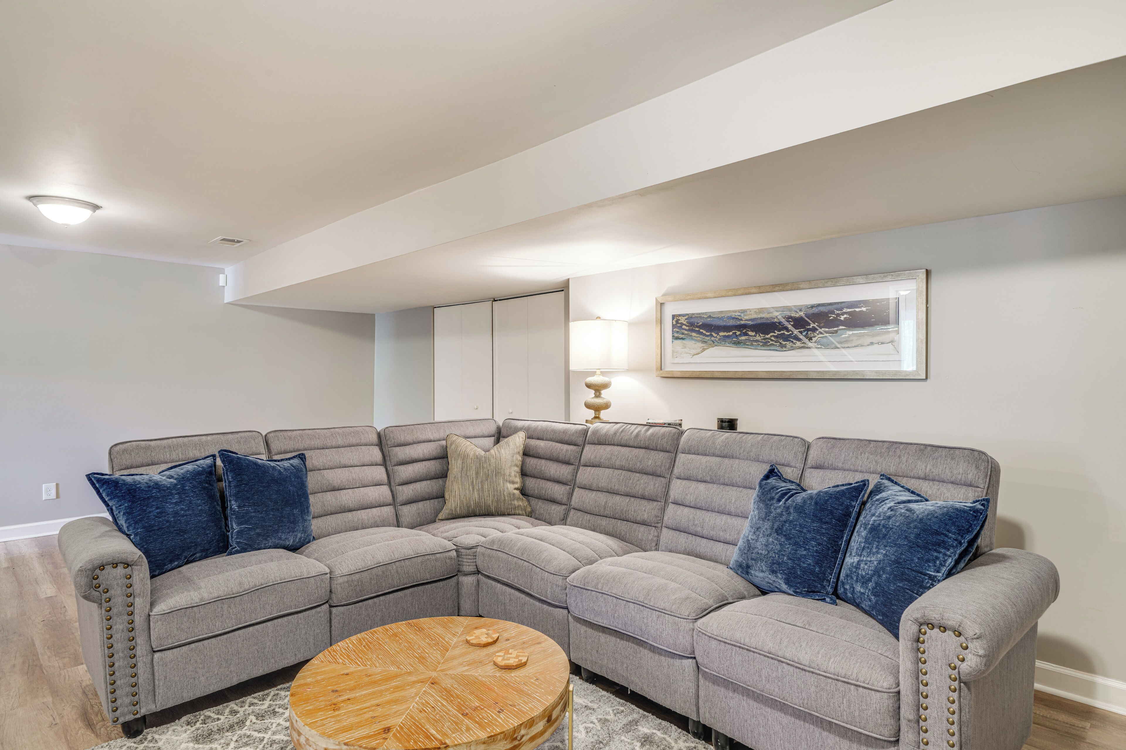 A modern living room with a sectional sofa, a round coffee table, and a framed picture on the wall.